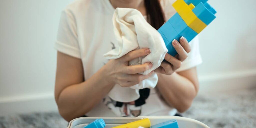 Na zdjęciu kobieta dokonująca dezynfekcji klocków do zabawy