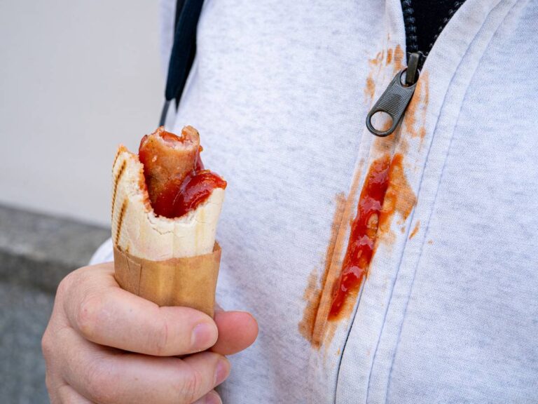Hot dog i plama na koszuli białej. Obrazek w artykule Jak usunąć plamy z sosu pomidorowego? Sposoby na plamy z sosu pomidorowego