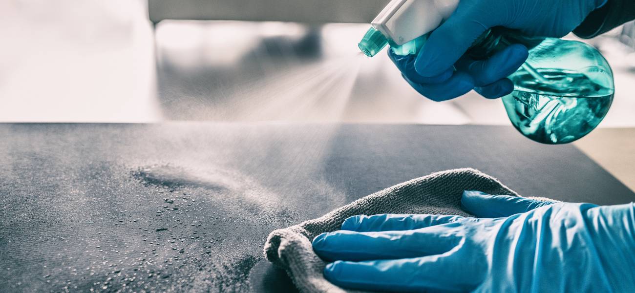 Na zdjęciu widoczna dłoń w rękawiczce. Trzyma ona ściereczkę i wyciera powierzchnię.