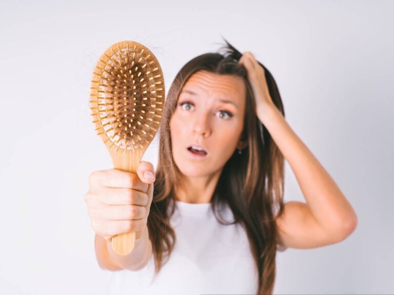 Kobieta ze szczotką. obrazek w artykule Co zazwyczaj dermatolog radzi na wypadanie włosów?